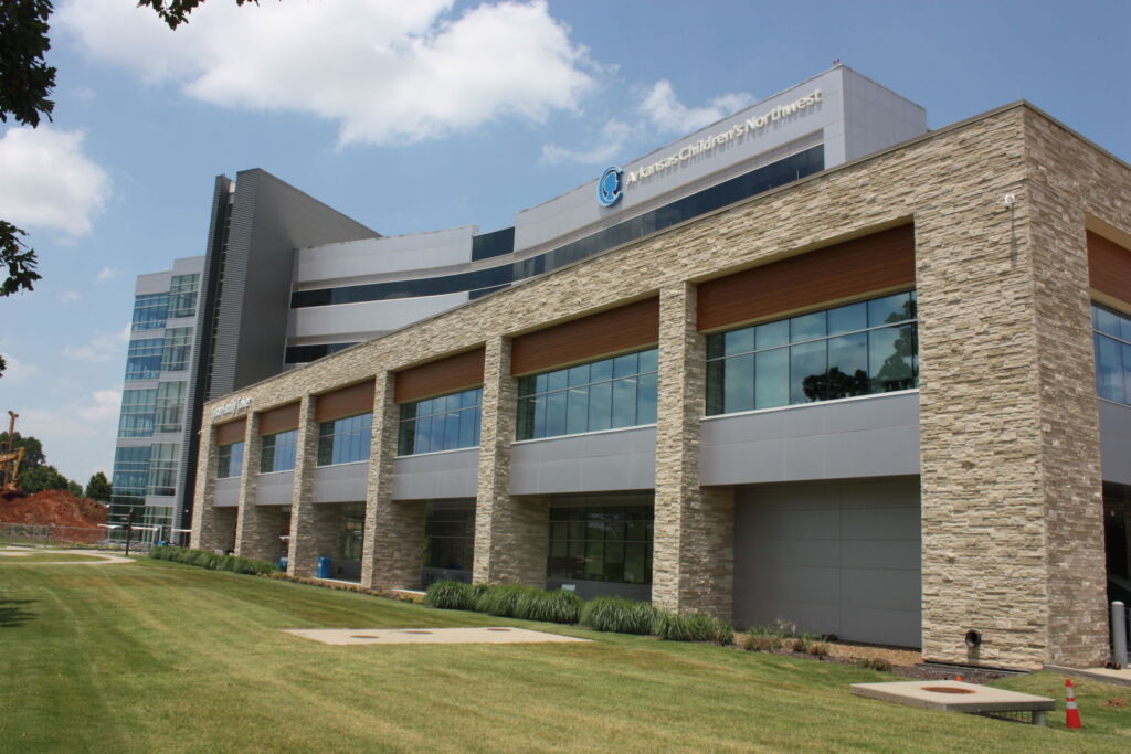 Arkansas Children's Northwest medical building faced with tan stacked stone veneer and tall windows beside a green lawn