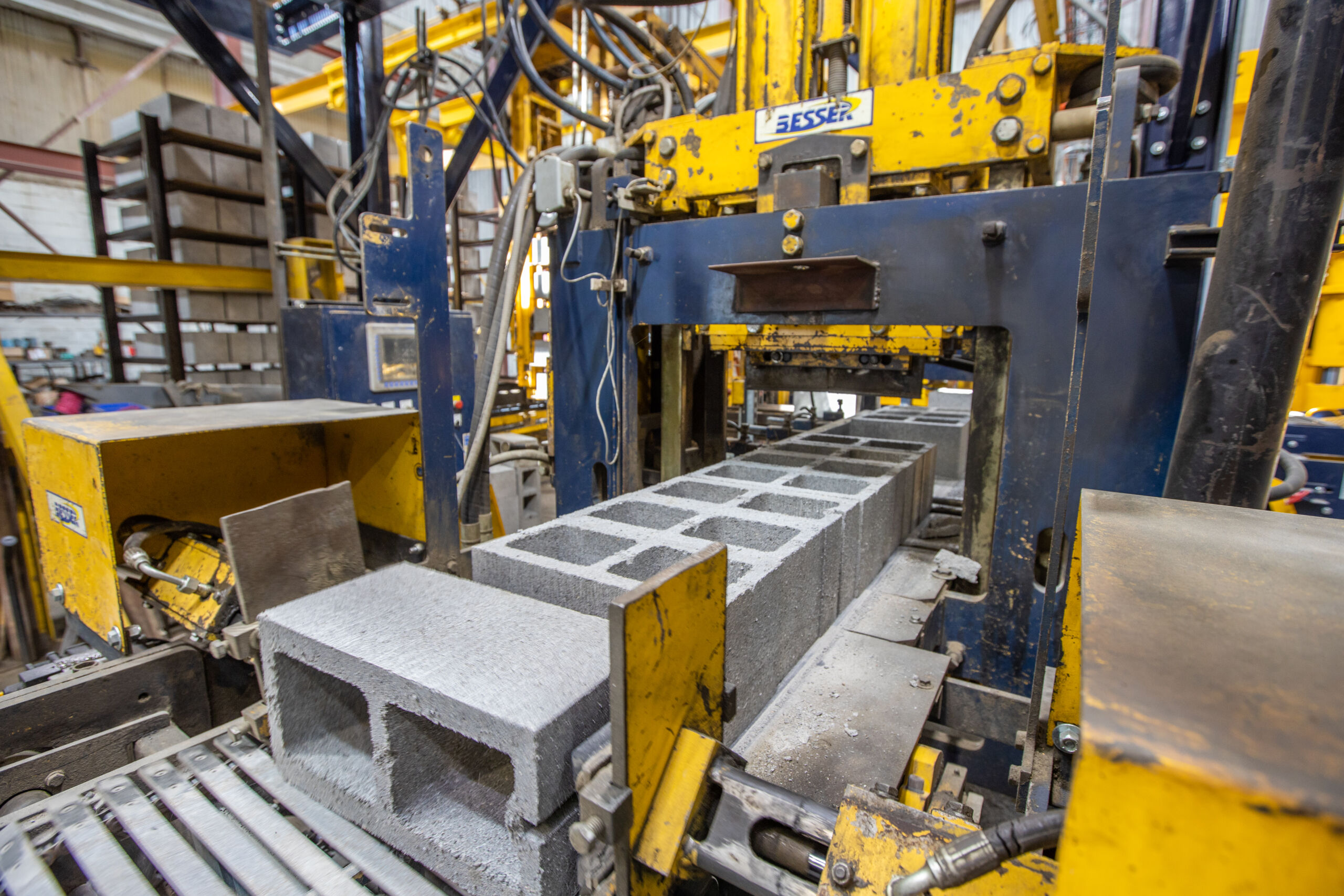 Freshly molded gray concrete blocks on the conveyor of a Besser block-making machine on a factory production line