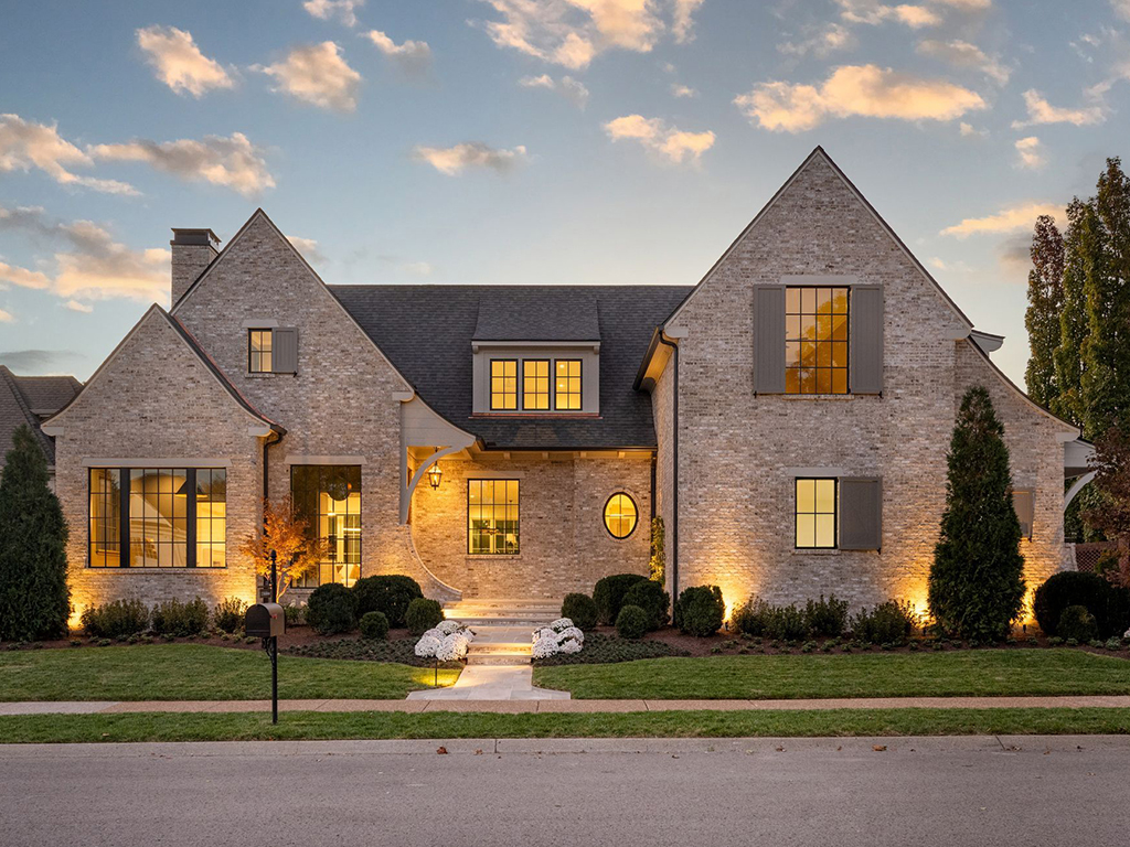 Two-story brick residence at dusk with stone façade and warm lighting