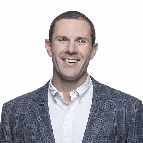 Portrait of Carson Cook, Antique Brick & Block team member, smiling in a gray plaid blazer