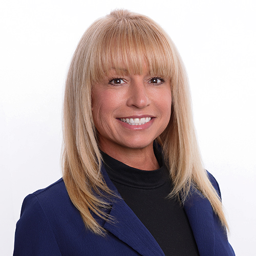 Portrait of Dawn Bowie, Antique Brick & Block team member, smiling in a navy blazer