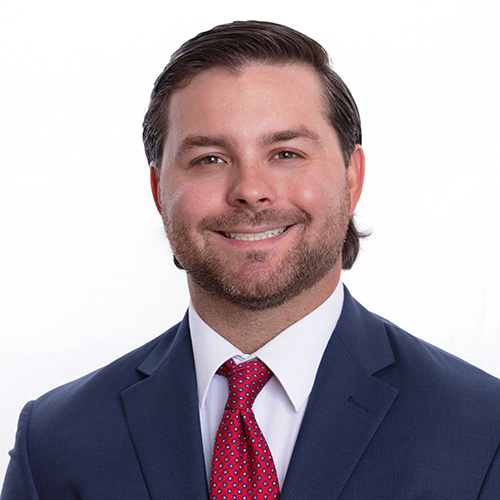 Portrait of Evan Wilson, Antique Brick & Block team member, in a navy suit with red tie